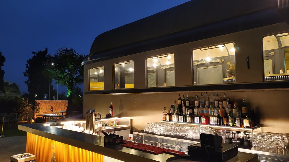 Il bancone bar esterno acceso all'ora blu, con i finestrini illuminati della carrozza sopra