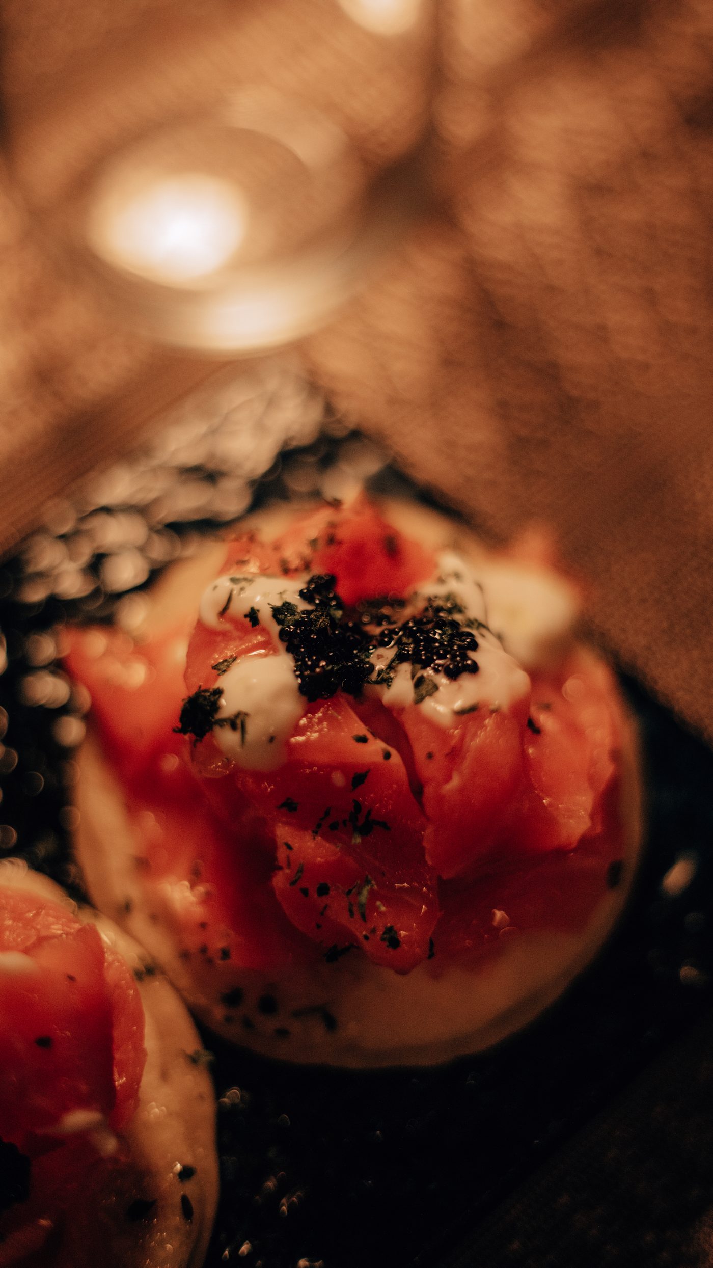 Dettaglio di un blino con salmone, panna acida e caviale, a lume di candela