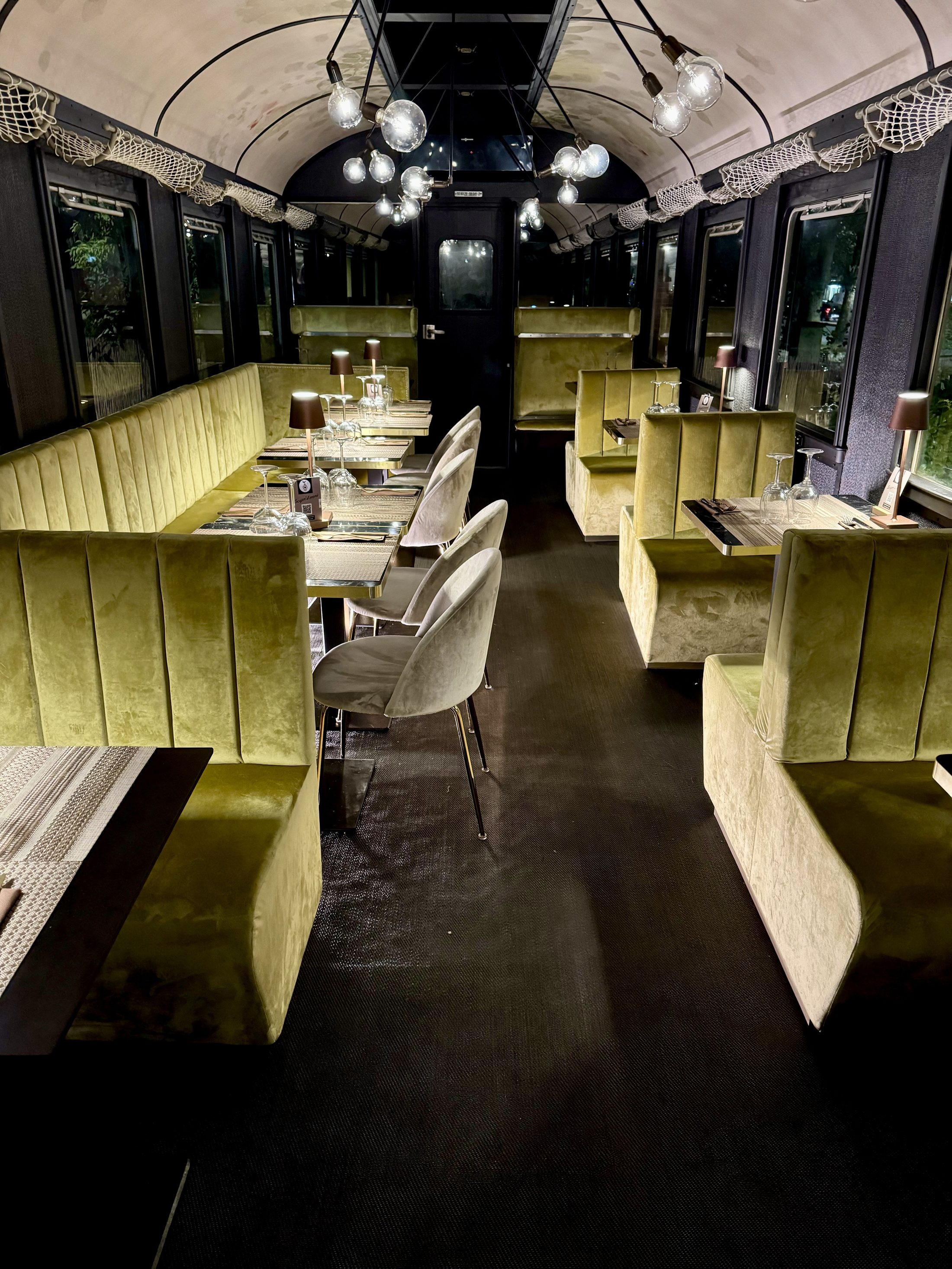 L'interno della carrozza: divanetti in velluto oro, lampadine sospese e tavoli apparecchiati