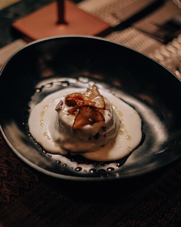 Flan di topinambur con crema di castelmagno, castagne e cioccolato bianco, servito in una ciotola nera